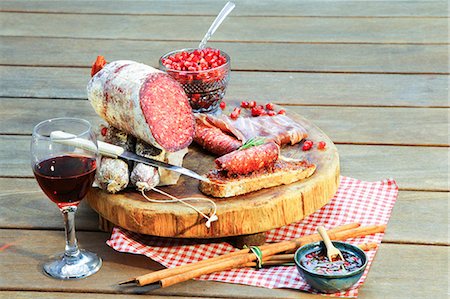 Salami on chopping board with wine and condiments Stock Photo - Premium Royalty-Free, Code: 649-06812414