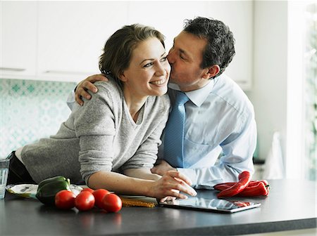 Businessman kissing wife in kitchen Stock Photo - Premium Royalty-Free, Code: 649-06829624