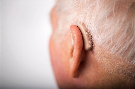 Senior man wearing hearing aid, close up Foto de stock - Sin royalties Premium, Código: 649-06829733