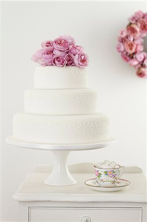 Three tiered wedding cake with pink floral arrangement and cup and saucer Foto de stock - Sin royalties Premium, Código: 649-06830140