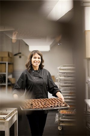 food manufacturing - Woman holding tray with chocolate Stock Photo - Premium Royalty-Free, Code: 649-06844316