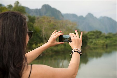 fotografare - Woman using camera phone, Nam Song River, Vang Vieng, Laos Fotografie stock - Premium Royalty-Free, Codice: 649-06844468