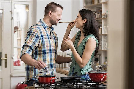 romantic couple indoors - Mid adult couple cooking dinner, tasting Stock Photo - Premium Royalty-Free, Code: 649-06844866