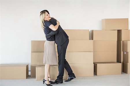 Businessman and -woman hugging in front of stack of cardboard boxes Stock Photo - Premium Royalty-Free, Code: 649-07064426