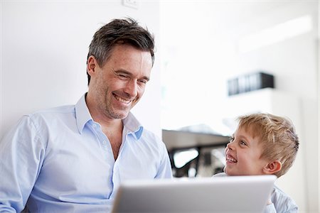 Man using laptop, son watching Stock Photo - Premium Royalty-Free, Code: 649-07064557