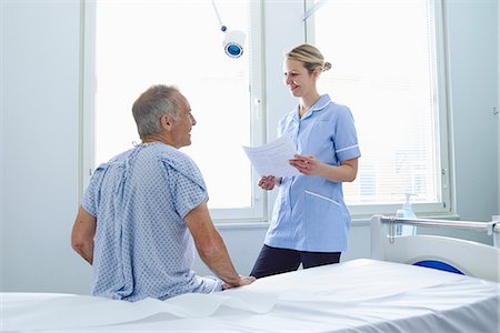 Nurse standing talking to patient sitting on hospital bed Photographie de stock - Premium Libres de Droits, Code: 649-07064699