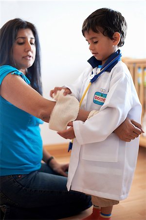 Boy dressed as doctor putting bandage on woman Stock Photo - Premium Royalty-Free, Code: 649-07064779