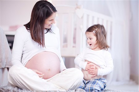 Pregnant mother and young daughter comparing bumps Photographie de stock - Premium Libres de Droits, Code: 649-07063641