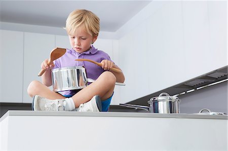 drum - Boy sitting on kitchen counter playing drums with pans and wooden spoons Stock Photo - Premium Royalty-Free, Code: 649-07118290