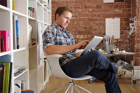 designer (interior, male) - Young man sitting on chair using digital tablet Stock Photo - Premium Royalty-Free, Code: 649-07118328