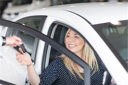 salesman customer car showroom - Young woman sitting in new car with key in showroom Stock Photo - Premium Royalty-Free, Code: 649-07119143