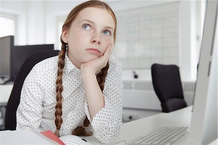 Girl with hand on chin looking up in office Stock Photo - Premium Royalty-Free, Code: 649-07119785