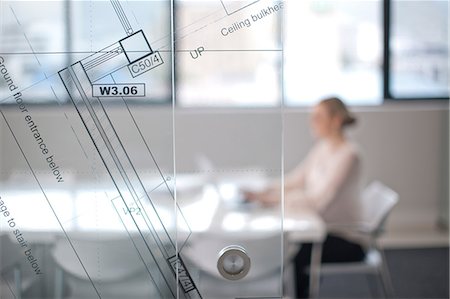 simsearch:649-07238396,k - Woman sitting at conference room table using laptop, view through window and architect plans Stock Photo - Premium Royalty-Free, Code: 649-07238397