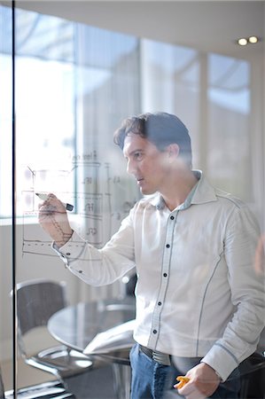 Man drawing architectural plans on glass wall Stock Photo - Premium Royalty-Free, Code: 649-07238408