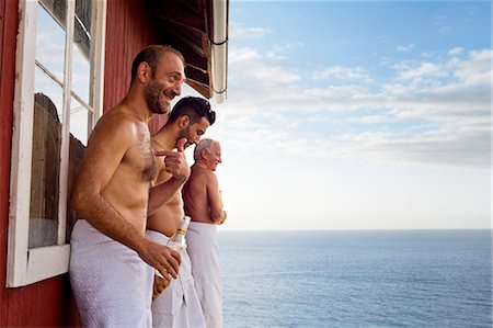 Three male friends standing outside sauna enjoying beer Stock Photo - Premium Royalty-Free, Code: 649-07238975