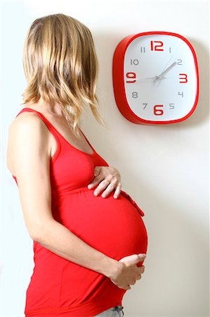 expecting - Pregnant woman clock watching in kitchen Stock Photo - Premium Royalty-Free, Code: 649-07239077