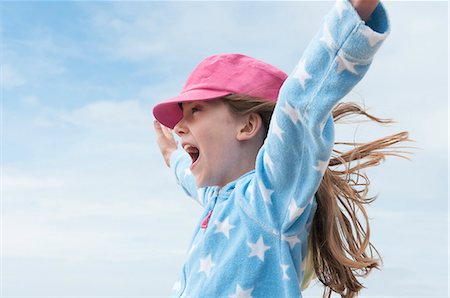 Girl wearing pink cap with arms raised in wind Photographie de stock - Premium Libres de Droits, Code: 649-07239443