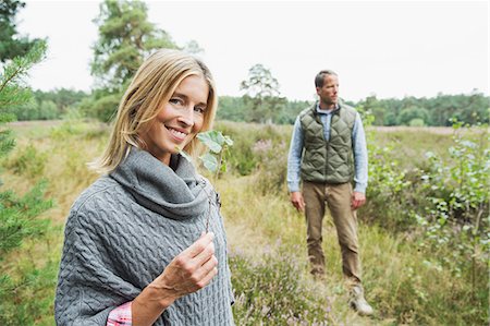 poncho - Mid adult woman holding leaf, man in background Stock Photo - Premium Royalty-Free, Code: 649-07239750