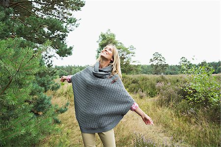 poncho - Mid adult woman wearing grey poncho looking up Stock Photo - Premium Royalty-Free, Code: 649-07239751