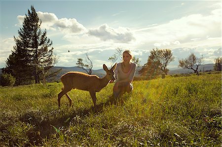 Young woman in field with fawn Stock Photo - Premium Royalty-Free, Code: 649-07239855