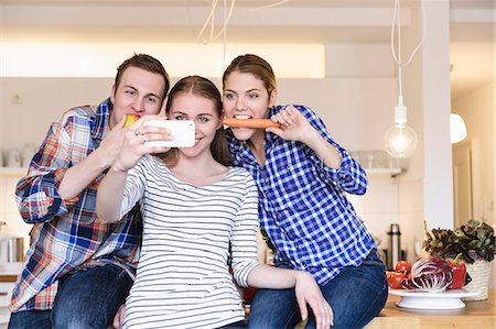 funny pose - Three young people having fun taking photographs in the kitchen Stock Photo - Premium Royalty-Free, Code: 649-07279560