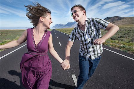 Mid adult couple running on road holding hands, Lanzarote, Spain Stock Photo - Premium Royalty-Free, Code: 649-07279730