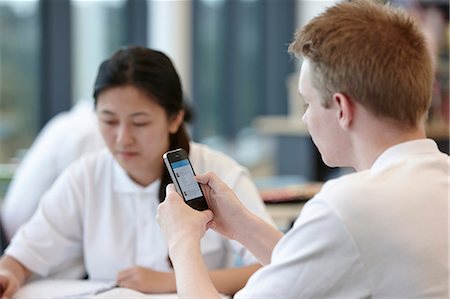 school girl back - Teenage boy using cell phone in classroom Stock Photo - Premium Royalty-Free, Code: 649-07280079