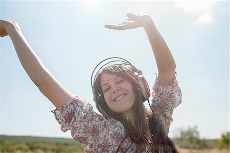 dancing women - Portrait of mid adult woman dancing in field wearing headphones with arms raised Stock Photo - Premium Royalty-Free, Code: 649-07280309