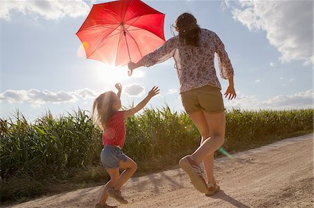 red - Mother and daughter walking through field carrying red umbrella Stock Photo - Premium Royalty-Free, Code: 649-07280316