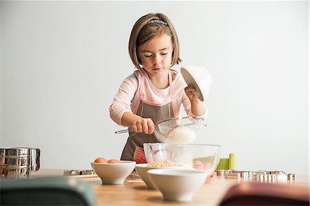 fun with flour - Girl sieving flour into mixing bowl Stock Photo - Premium Royalty-Free, Code: 649-07280347