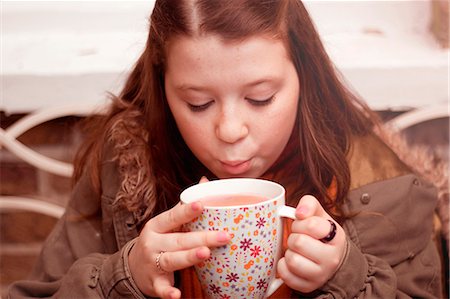 Teenage girl blowing on mug of coffee outdoors Stock Photo - Premium Royalty-Free, Code: 649-07280393