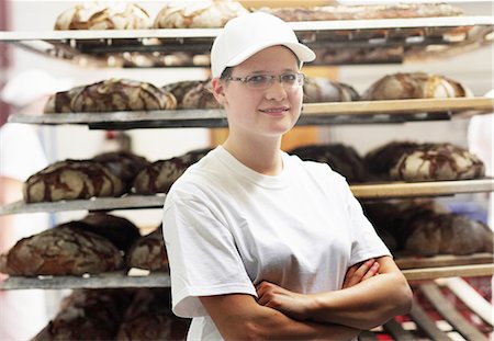 Baker standing in front of bread on shelves with arms folded Stock Photo - Premium Royalty-Free, Code: 649-07280433