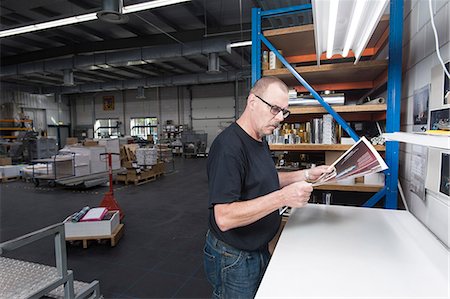 press - Worker checking quality of print products in printing workshop Stock Photo - Premium Royalty-Free, Code: 649-07280528