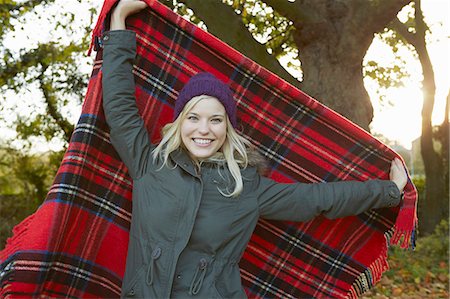 parka - Portrait of young woman in park, holding up tartan picnic blanket Stock Photo - Premium Royalty-Free, Code: 649-07280746