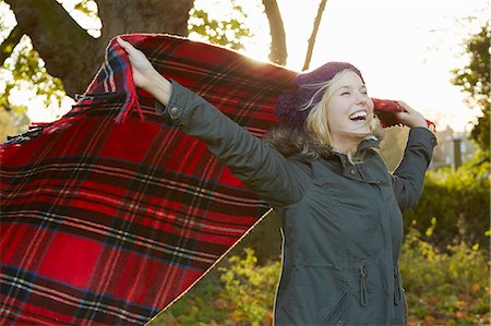 parka - Portrait of young woman in park, holding up tartan picnic blanket Stock Photo - Premium Royalty-Free, Code: 649-07280747