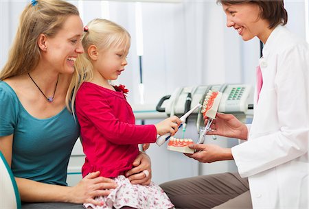 dentures - Dentist teaching girl on mothers lap how to brush teeth Stock Photo - Premium Royalty-Free, Code: 649-07280856