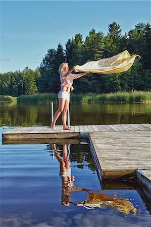 Young woman shaking blanket on pier, Gavle, Sweden Foto de stock - Sin royalties Premium, Código: 649-07280979