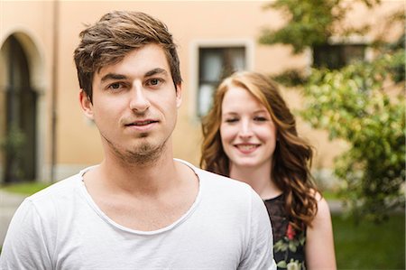 Portrait of young man with girlfriend standing in background Stock Photo - Premium Royalty-Free, Code: 649-07436302