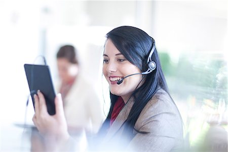 Businesswoman using digital tablet and having telephone conversation on headset Stock Photo - Premium Royalty-Free, Code: 649-07436532