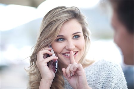 silence - Young woman on phonecall with finger to lips Stock Photo - Premium Royalty-Free, Code: 649-07436545