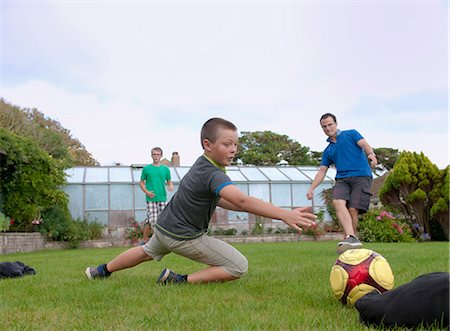 simsearch:649-07804673,k - Father and sons playing football in garden Photographie de stock - Premium Libres de Droits, Code: 649-07436691