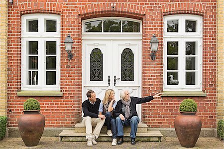 front door house - Father and mid adult couple sitting on doorstep Stock Photo - Premium Royalty-Free, Code: 649-07436796