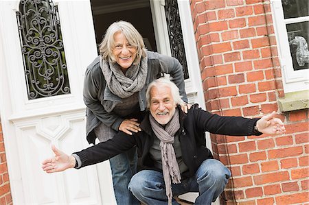 Senior couple by front door, man crouching with open arms Stock Photo - Premium Royalty-Free, Code: 649-07436810