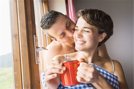 romantic women in windows - Young couple sharing a kiss in holiday chalet, Tyrol, Austria Stock Photo - Premium Royalty-Free, Code: 649-07437145