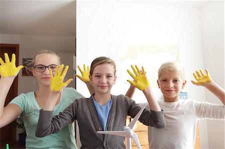 Two sisters and brother with yellow sunshine hands and a model of wind turbine Stock Photo - Premium Royalty-Free, Code: 649-07437298