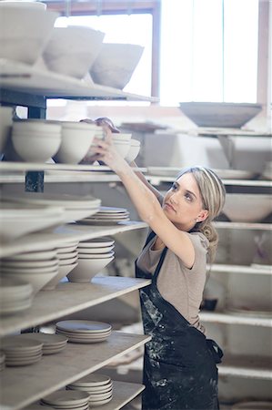 Potter stacking bowls onto shelf at crockery factory Stock Photo - Premium Royalty-Free, Code: 649-07437452