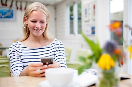 Young woman in cafe looking at mobile phone Stock Photo - Premium Royalty-Free, Code: 649-07437832