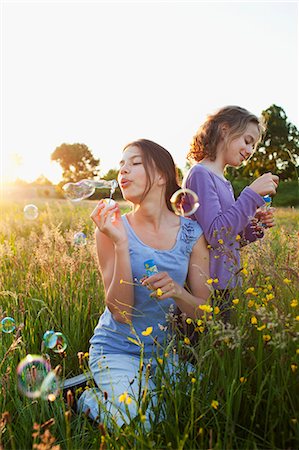 Sisters blowing bubbles in field Stock Photo - Premium Royalty-Free, Code: 649-07437904