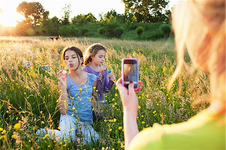 family  fun  outside - Mother taking photograph of girls blowing bubbles Stock Photo - Premium Royalty-Free, Code: 649-07437905