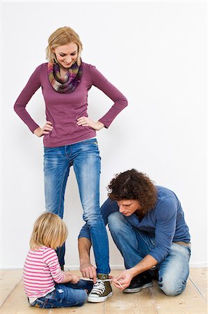 Studio portrait of mother having shoe laces tied Fotografie stock - Premium Royalty-Free, Codice: 649-07520661